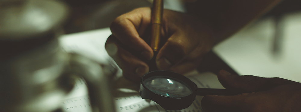 Close up of person using magnifying glass while highlighting in book