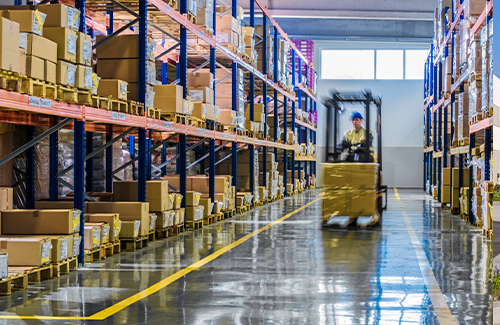 Worker driving lift on warehouse floor