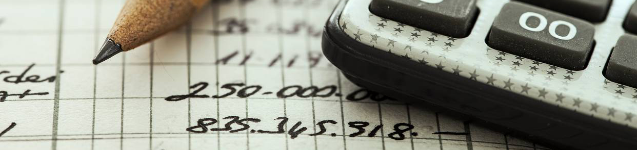 Extreme close up of a calculator and pencil on top of a paper filled with numbers