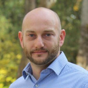 Man with collared shirt in front of trees